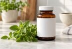 Fresh oregano leaves beside a plain unbranded supplement bottle.