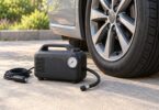 Generic portable tire inflator with disconnected hose and power cord beside a parked car wheel.