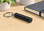 Illustration of a small black keychain pointer switched off beside a notebook.