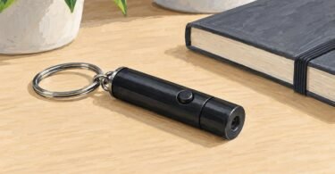 Illustration of a small black keychain pointer switched off beside a notebook.