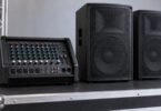 Generic unbranded audio mixer beside two loudspeaker cabinets.