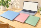 Illustration of generic blue, pink and green laptops on a desk.