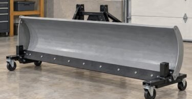 Illustration of a detached snowplow blade resting on wheeled supports in a garage.