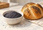Illustration of a bowl of culinary poppy seeds beside seeded bread.