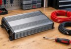 An unbranded compact silver amplifier beside unconnected power cables.