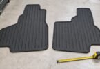 Two generic rubber floor mats beside a measuring tape.