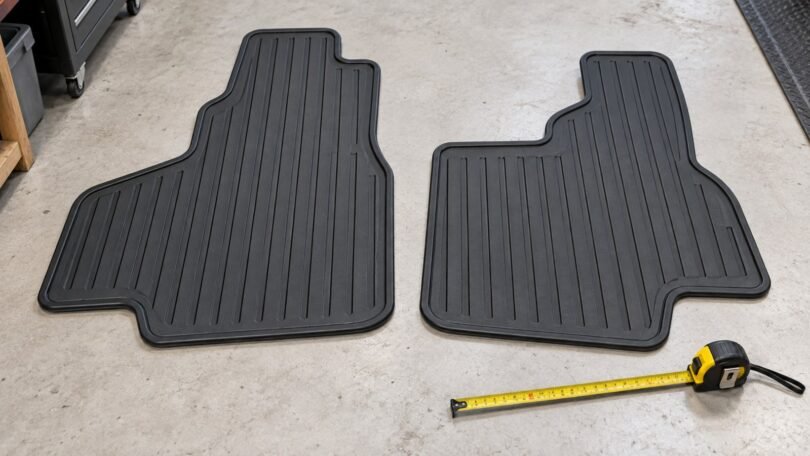 Two generic rubber floor mats beside a measuring tape.