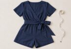 Generic navy wrap-style adult romper laid flat beside a tape measure.