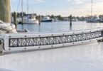 Generic curved white auxiliary LED light bar on a dockside workbench.
