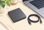 Illustration of a generic portable external drive and USB cable beside a laptop.