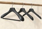 Illustration of black wooden hangers with metal hooks and a trouser bar.