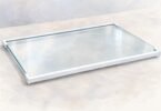 Illustration of a clear glass refrigerator shelf with white edge trim, shown detached on a pale surface.