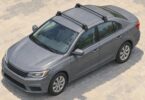 Illustration of two transverse roof-rack crossbars on a generic gray sedan.
