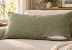 Rectangular sage pillow cover with a partly open zipper revealing its insert on a couch.