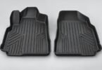 Two generic black molded automotive floor liners on a light gray surface.
