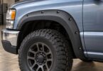 Black bolt-style fender flare around the front wheel arch of a generic silver-blue pickup truck.