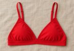 A plain red triangle bralette laid flat on neutral linen.