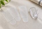 Generic transparent adhesive strips beside an unbranded clear plastic hook.