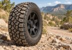 A generic all-terrain tire and dark wheel on a gravel trail.