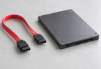 Red SATA data cable with black keyed connectors beside a generic 2.5-inch SSD