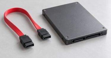 Red SATA data cable with black keyed connectors beside a generic 2.5-inch SSD
