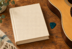 Illustration of a closed plain music-reference book beside a guitar pick and the edge of an acoustic guitar.