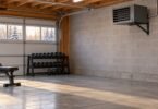Generic electric heater mounted high on a masonry garage wall with a clear floor area and exercise equipment farther away.
