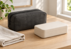 A closed charcoal storage pouch and cream case beside a folded cloth on a wooden table.