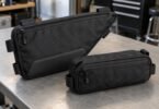 Two unbranded black zippered storage pouches, one triangular and one rectangular, resting on a gray workbench.