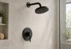 Illustrative unbranded matte-black showerhead and lever trim on a pale tiled wall
