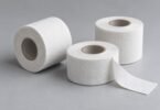 Illustration of plain white cloth tape rolls with an unrolled end on a gray surface.