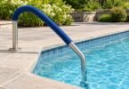 A blue fabric sleeve fitted above the waterline on a generic stainless-steel pool handrail.