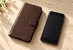 Unbranded brown closed phone folio beside a generic black handset on a stone surface