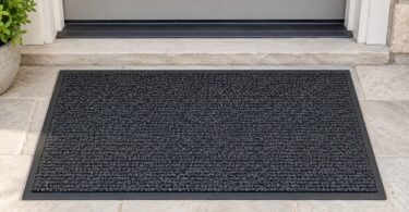 Illustration of a plain charcoal entry mat lying flat on a dry stone doorstep.