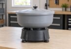 Illustration of a gray, lidded vibratory tumbler on a workshop bench.