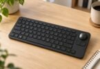 Unbranded black compact keyboard with a spherical trackball and two mouse buttons on a wooden desk.