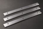 Illustration of three generic straight planer knives on a gray surface.