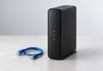 Unbranded black cable internet gateway beside a blue Ethernet cable on a pale tabletop