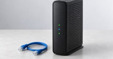 Unbranded black cable internet gateway beside a blue Ethernet cable on a pale tabletop