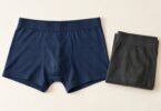 Illustration of unbranded navy boxer briefs and folded charcoal underwear on a cream background