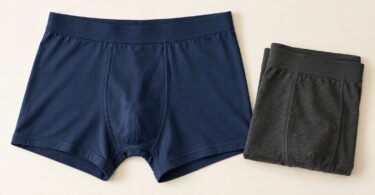 Illustration of unbranded navy boxer briefs and folded charcoal underwear on a cream background