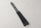 Illustration of a generic blunt butterfly practice trainer with a rounded perforated insert on a pale tabletop