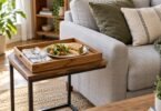 Illustration of a wooden serving tray with a sandwich and salad on a side table beside a gray sofa