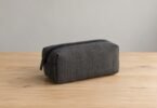Illustrative image of a closed, unbranded gray storage pouch on a wooden table.