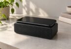 Illustrative unbranded smartphone resting on a compact tabletop speaker.