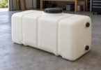 An unbranded rectangular plastic storage tank with capped fittings on a workshop floor