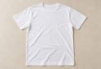 Illustrative blank adult white crewneck T-shirt laid flat on a beige surface.