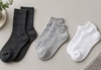 Illustrative flat lay of unbranded charcoal crew, gray quarter-height and white low-cut socks.