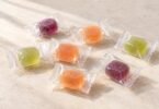 Individually wrapped purple, orange and green candies on a cream tabletop