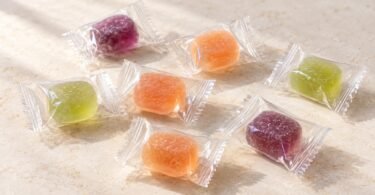 Individually wrapped purple, orange and green candies on a cream tabletop